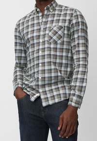 Karohemd in Grau-, Blau- und Brauntönen mit Knöpfen, einer einzelnen Brusttasche und weichem Baumwollmaterial.