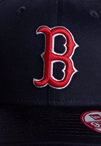 Cappello della marina con una grande "B" rossa ricamata e contornata di bianco. Tessuto morbido con un visiera texturizzata e un'etichetta circolare sul lato interno.