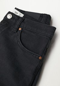 Jeans de denim negro con un diseño clásico de cinco bolsillos, que presentan remaches de tono cobre, un cierre de botón y una etiqueta blanca en el interior de la cinturilla.