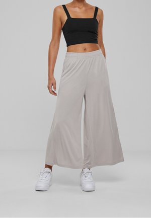 Czarny crop top z kwadratowym dekoltem, zestawiony z jasnoszarymi spodniami typu wide-leg, wyposażonymi w elastyczny pas i gładką fakturę, uzupełniony białymi sneakersami.