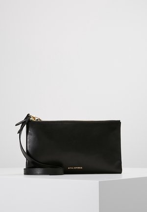 Bracelet rectangulaire en cuir noir avec fermeture éclair dorée et petit logo doré "Royal Republiq" sur le devant, posé sur une surface blanche.