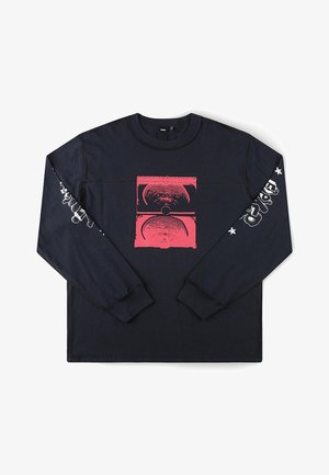 Chemise noire à manches longues avec un graphisme abstrait de haut-parleur rouge sur le devant et du texte stylisé blanc ainsi que des étoiles le long des deux manches.