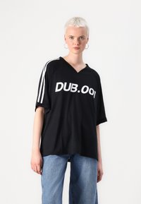 Melns oversize t-krekls ar V veida kakla izgriezumu un baltu "DUB.001" tekstu. Piedurknēm ir baltas svītras. Izgatavots no mīksta auduma.