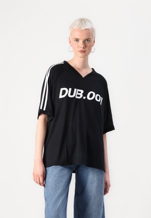 Melns oversize t-krekls ar V veida kakla izgriezumu un baltu "DUB.001" tekstu. Piedurknēm ir baltas svītras. Izgatavots no mīksta auduma.