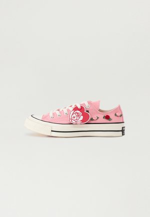 Roze canvas sneakers met witte veters, voorzien van decoratieve borduursels van rozen en een hartvormig patch, zwarte rand op de zool.