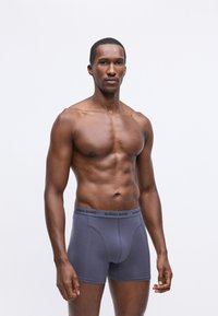 Szürke férfi boxer alsónadrág elasztikus derékpánttal, amelyen a "BJÖRN BORG" márkázás található, sima anyagból készült, és testhezálló fazonú.