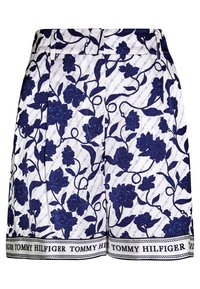 Vita shorts med mörkblå blommönster, bälteshällor och "Tommy Hilfiger"-text längs nederkanten.