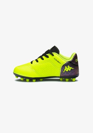 Chaussure de football jaune vif et noire avec crampons, lacets noirs, texte "KOMBAT" et un logo sur le talon avec un motif géométrique foncé.
