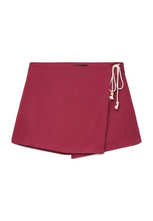 Jupe courte portefeuille rouge avec cordons de serrage blancs ornés de perles en bois sur le côté, posée à plat sur fond blanc.