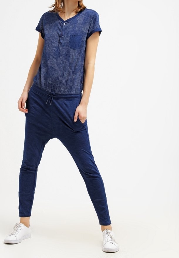 Námořnické modré tričko s krátkým rukávem a kapsou; volné kalhoty s nízkým rozkrokem a elastickým pasem; doplněné bílými teniskami.