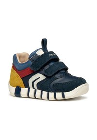 Zapatilla deportiva azul marino con acentos de ante en amarillo y rojo, con dos correas de velcro, un logotipo blanco y una suela texturizada.