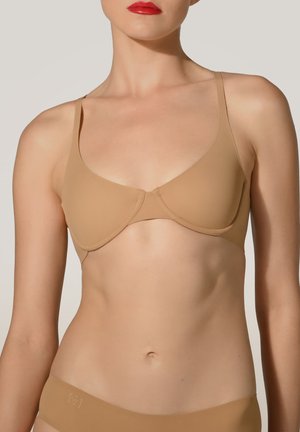 Nøgen underwire bh med glat, matte finish og justerbare stropper. Har et minimalistisk design med en sømløs fremtoning.