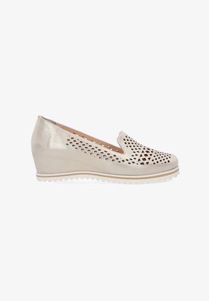 Zkosená slip-on obuv v metalické stříbrné kůži s výřezovými geometrickými vzory a bílou gumovou podrážkou s texturovaným okrajem.