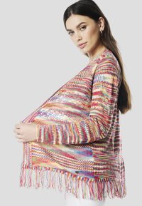 Meer kleurige gebreide cardigan met een franjerand. Kenmerkt zich door een gestructureerd patroon in roze, rood, blauw en geel garen, met een open voorkant.