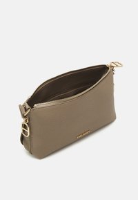 Beige gestikt leren clutch met gouden hardware, ritssluiting en logo-detail. Heeft een gladde textuur en een minimalistisch ontwerp.