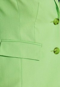 Hellgrünes Blazer-Jackett mit zwei grünen Knöpfen und einer horizontalen Klappentasche aus strukturiertem Stoff.