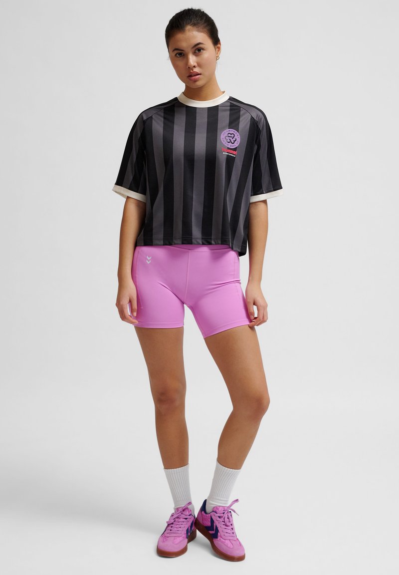 Svart och grårandig kortärmad skjorta med vit krage, parat med rosa träningsshorts. Har logotyp och texturerade ytor.