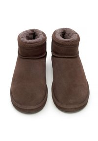 Stivali alla caviglia in camoscio marrone con morbida fodera in pelliccia, punta arrotondata e dettagli cuciti lungo il bordo superiore. Suola in gomma piatta per il massimo comfort.