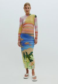 Robe à manches longues avec un imprimé de coucher de soleil coloré et des fleurs ; présente des nuances de rose, jaune, bleu et vert, fabriquée dans un tissu lisse.