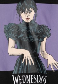 Maglietta grafica con un'illustrazione di un personaggio con capelli scuri, che indossa una blusa nera a volanti su uno sfondo viola, etichettata "MERCOLEDÌ".