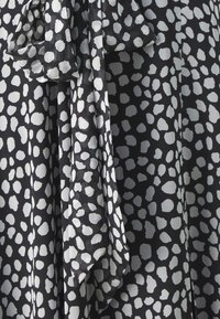 Schwarzer Stoff mit einem verstreuten, unregelmäßigen Punktemuster in Weiß. Leicht und falls, mit weicher Textur und fließendem Design.