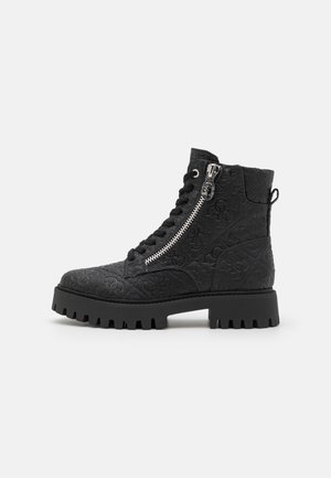 Bottes noires à la cheville avec un motif texturé, dotées de lacets et d'une fermeture éclair sur le côté, semelle en caoutchouc épaisse avec des crampons prononcés, et un design durable.