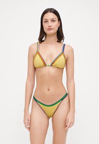Completo bikini giallo con coppe triangolari e spalline sottili, decorato con dettagli di cuciture colorate in verde, viola e blu.