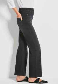 Pantalons en denim noir avec une coupe décontractée, taille élastique et poches latérales. Présentent des coutures visibles et une subtile décoration de poche.