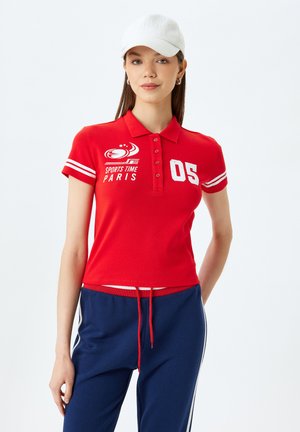 Rode polo shirt met korte mouwen, voorzien van witte strepen en de print "SPORTS TIME PARIS" samen met het nummer "05". Casual fit.
