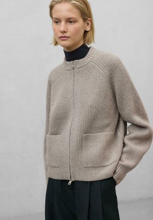 Hellbeige gerippter Strickcardigan mit hohem Kragen, Reißverschluss und Fronttaschen. Verfügt über eine lockere Passform und strukturierten Stoff.