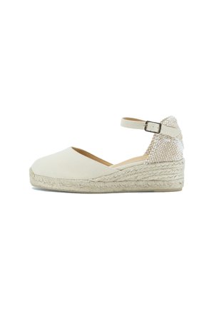 Espadrillas a zeppa in tela beige con suola in juta intrecciata, cinturino alla caviglia e dettagli testurizzati sul retro. Finitura liscia, design con punta arrotondata.