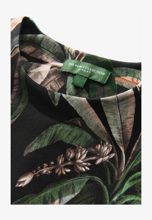 Sort stof-topp med et tropisk bladmønster i grønne og brune nuancer, med et grønt mærke der står "THE KEW COLLECTION by NEXT."