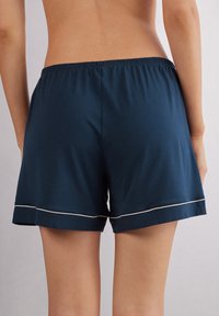 Marineblauwe katoenen shorts met een elastische tailleband en witte rand langs de zoom, voorzien van een ontspannen pasvorm en een soepele textuur.