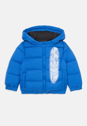 Giacca a vento blu con cappuccio, dotata di chiusura a zip frontale, polsini elasticizzati e una grande stampa bianca del logo sul lato sinistro. Fodera interna nera.