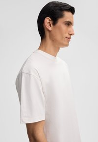 Lichtbeige katoen t-shirt met een ronde hals, korte mouwen en een relaxte pasvorm, met een soepele textuur en zonder zichtbare patronen.
