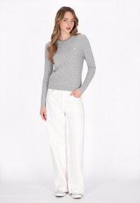 Grauer gerippter Pullover mit langen Ärmeln, rundem Ausschnitt und kleinem Ankerlogo. Kombination aus weißen weit geschnittenen Hosen und grauem Schuhwerk.