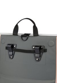 Szürke vízálló táska, amely tetején fogantyúval, fekete hardverrel, állítható pánttal és varrott részletekkel rendelkezik. Biztonságos záródású és lapos kialakítású.