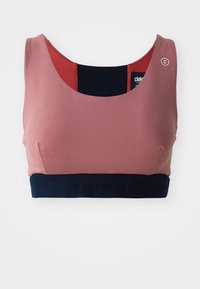 Sport bra in soft pink fabric with a wide navy band. Features a scoop neckline and contrasting red accent at the back.