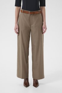 Beežid laia säärega püksid esiplekidega, valmistatud siledast kangast. Sobitatud pruuni seemisnahast vöö ja pruunide terava ninaosaga saapadega.