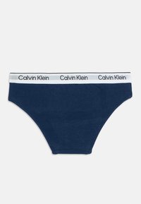 Sötétkék Calvin Klein boxer alsónemű fehér rugalmas derékpánttal, melyen ismétlődő fekete Calvin Klein logó felirat található.