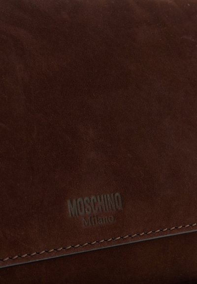 Smeđa suđena tašna sa reljefnim logotipom "Moschino Milano". Ima glatku teksturu i šivenu detalj uz rub.