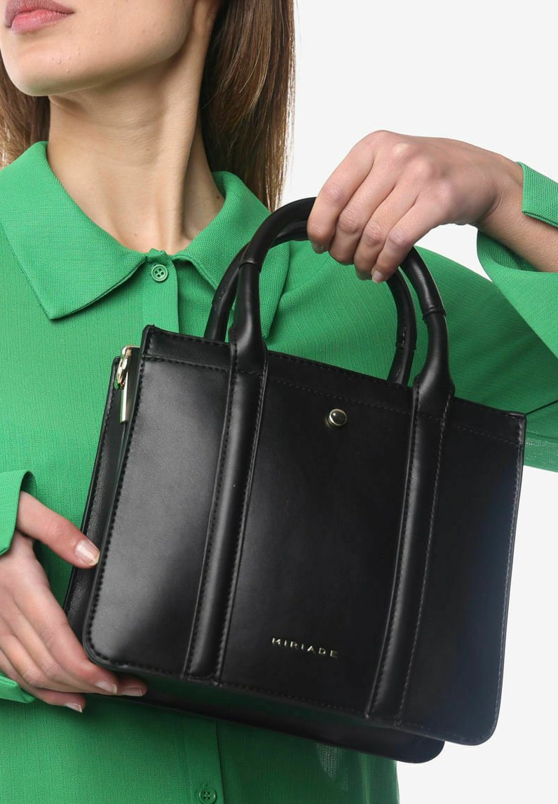 Sort læderhandbag med struktureret design, to hanke og metalaccenter. Har lodret syning og et diskret brandlogo.