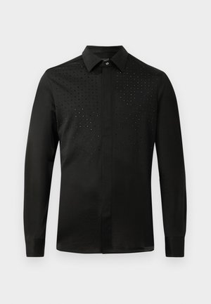 Chemise noire à manches longues avec un col classique, des boutons dissimulés et de subtils embellissements cloutés sur la partie supérieure avant.