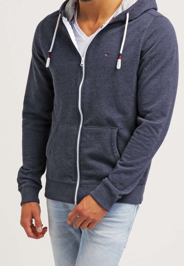 Granatowy hoodie na zamek z szarym wyściełanym kapturem, dwoma przednimi kieszeniami, białymi sznurkami oraz ściągaczami przy mankietach i dolnej krawędzi. Casualowy krój.