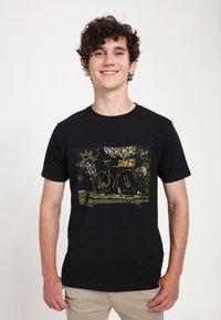 T-shirt nera con un design grafico di una bicicletta gialla su uno sfondo verde a motivo, con testo e accenti in stile graffiti.