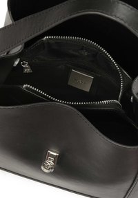 Fekete bőr kézitáska, strukturált formával. Ezüst hardware zár és logó mintával bélelt cipzáras zsebek találhatók rajta.