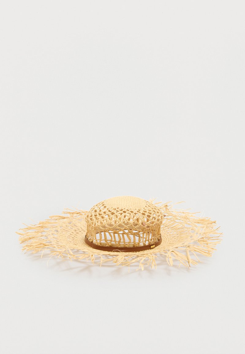 Chapeau en paille tressée à larges bords avec bords frangés et motif ajouré autour de la calotte, présenté sur un fond uni.