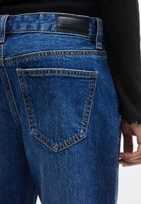 Τζιν παντελόνια σε βαθύ μπλε χρώμα με διακριτικό ξεθώριασμα. Διαθέτουν κλασική ραφή, δύο πίσω τσέπες και μαύρο δερμάτινο ετικέτα μάρκας στη μέση.