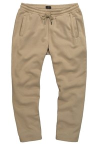 Béžové tepláky z měkkého materiálu, s elastickým pasem na šňůrku a dvěma bočními kapsami. Subtilní brandingový detail na noze.