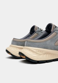 Baskets en suède gris et mesh, dotées d'une semelle intermédiaire épaisse de couleur blanc cassé et d'une semelle extérieure en caoutchouc noir ; arborent un logo de marque bien visible sur le talon.